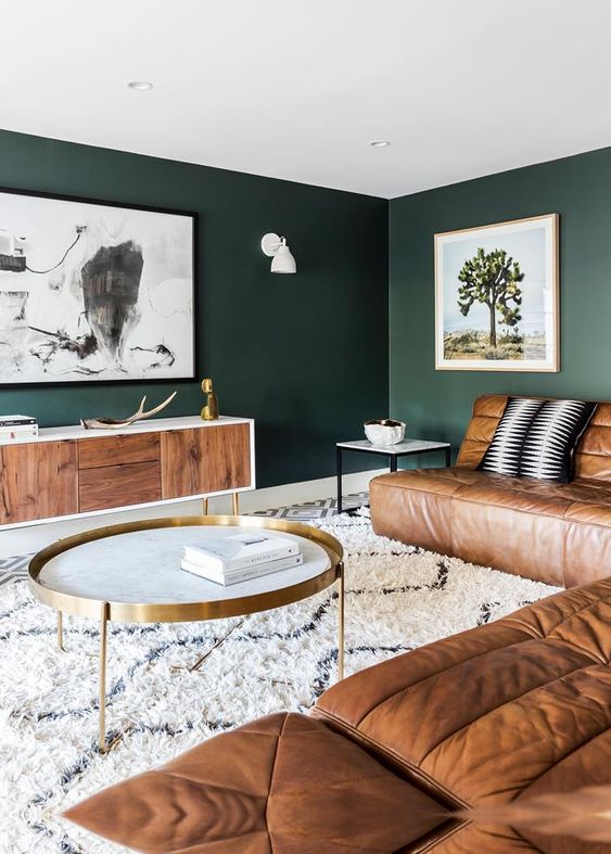 a stylish living room with dark green walls and a large leather sofa that defines the whole space