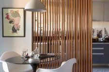 23 a vertical wooden plank screens gently separates the kitchen and the dining space