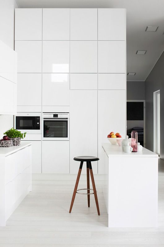 a high gloss white kitchen with tall wall cabinets and an island