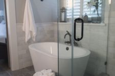 24 the bathtub space covered with marble tiles that match the painted grey walls
