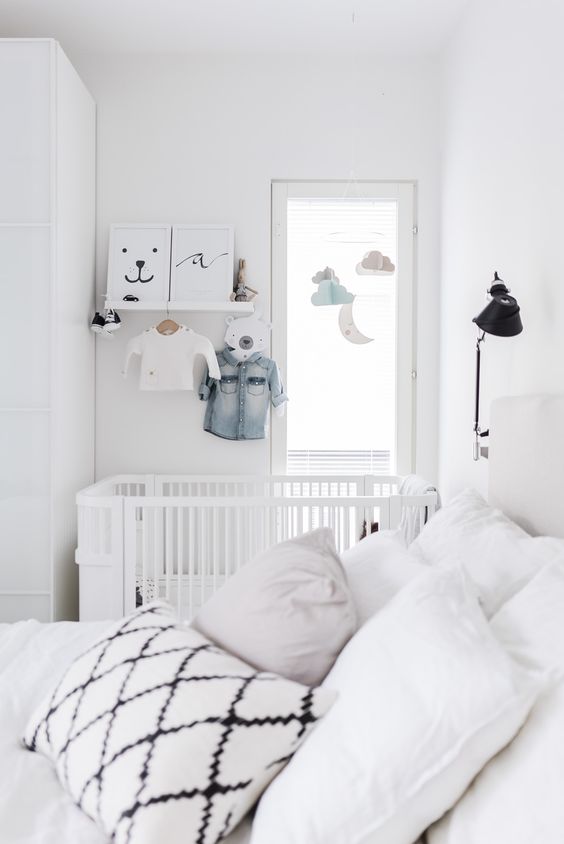 a small Scandinavian bedroom with a baby's nook with a crib, shelves, a mobile and a wardrobe