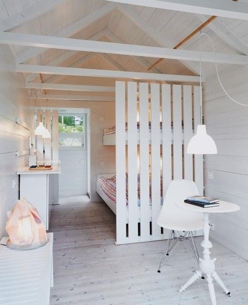 a white wooden plank screen gently separates a small shabby chic studio space