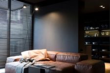 25 the living room is defined by a stylish brown leather sofa and black walls