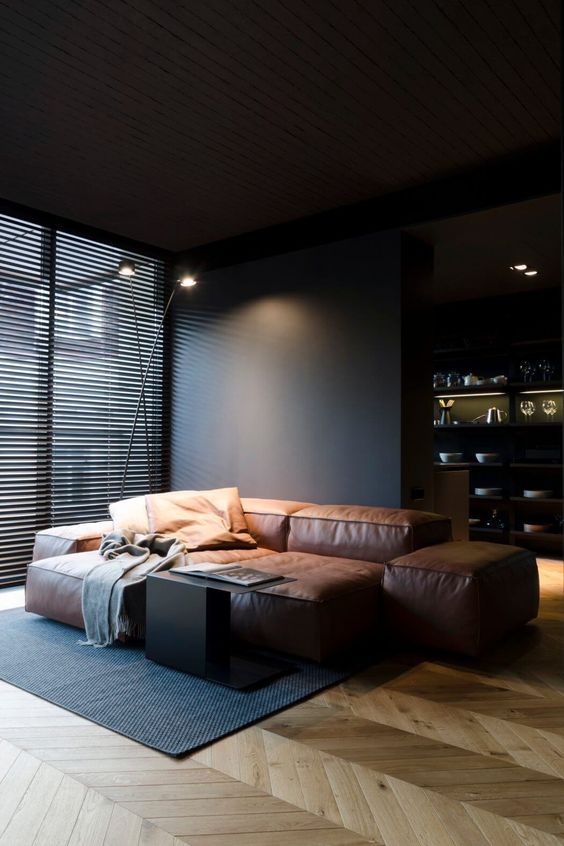 the living room is defined by a stylish brown leather sofa and black walls