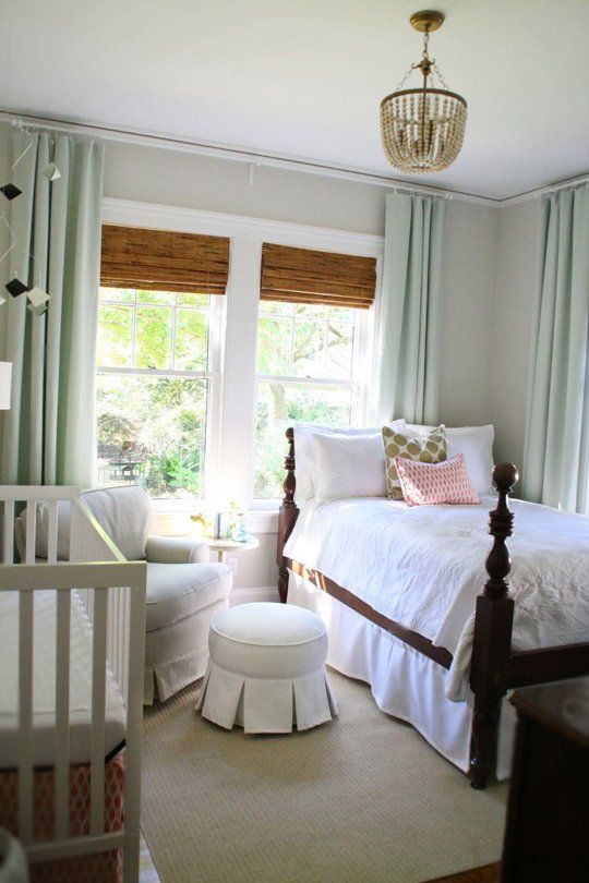 a traditional farmhouse bedroom with a crib by the wall and a comfy chair with an ottoman