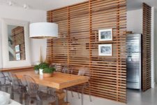 26 the dining space is made uncluttered with horizontal wooden plank screens that separate it from the kitchen