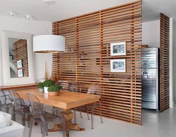 the dining space is made uncluttered with horizontal wooden plank screens that separate it from the kitchen