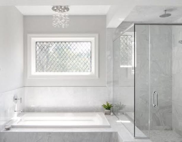 white marble tiles in the shower are extended to make a backsplash and cover the bathtub, too
