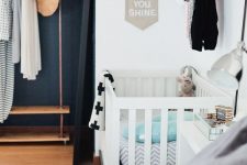 a cool master bedroom with a makeshift closet, a bed with neutral bedding, a crib with printed bedding, a shelf and some decor