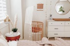 a lovely neutral boho bedroom with a bed and neutral bedding, a nigthstand with decor, a stained crib, a dresser as a changing table