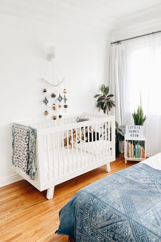 a master bedroom with a small nursery nook, a crib, a mobile, potted plants and a bookshelf is a lovely space