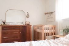 a minimal neutral bedroom with a stained dresser, a stained crib, a bed with neutral bedding and nightstands