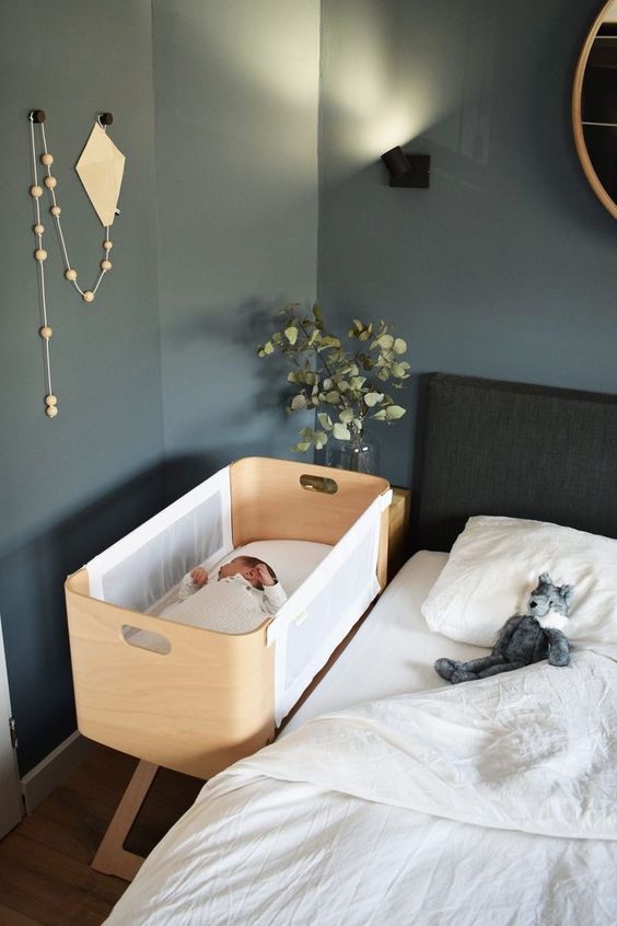 a stylish grey modern bedroom with a black bed and white bedding, a plywood crib and some boho decor around