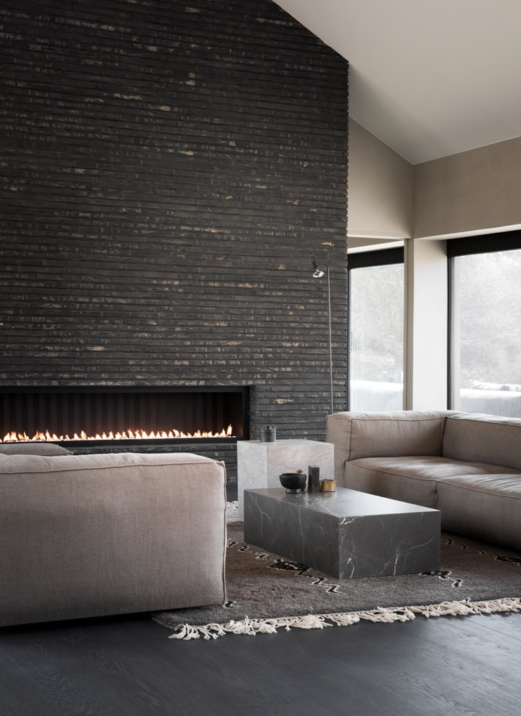This fantastic living room features a wood clad fireplace, stone coffee tables and moody tones all over