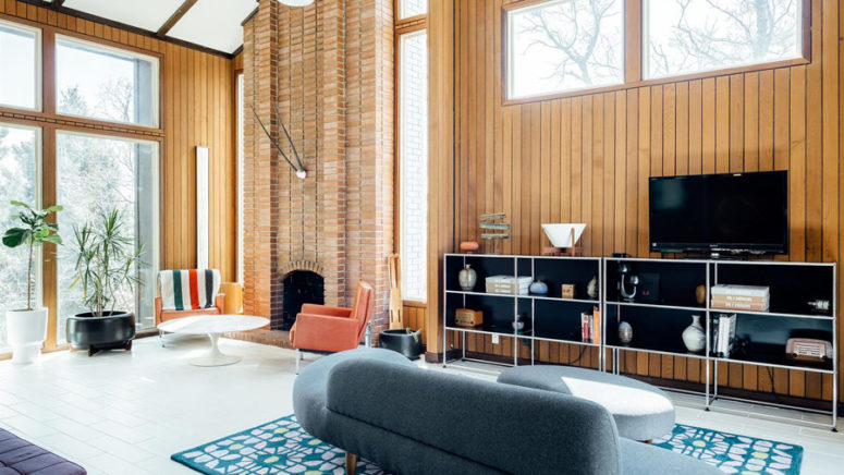 The living space is done with a brick clad fireplace and muted colored mid-century modern furniture