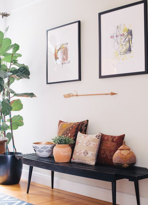 a black bench, colorful pillows, potted plants, artworks and an arrow