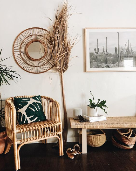 A boho desert entryway with rattan furniture, cacti artworks, potted plants and grasses