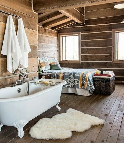 a chalet bedroom fully clad with wood with a vintage clawfoot tub that adds interest to the space