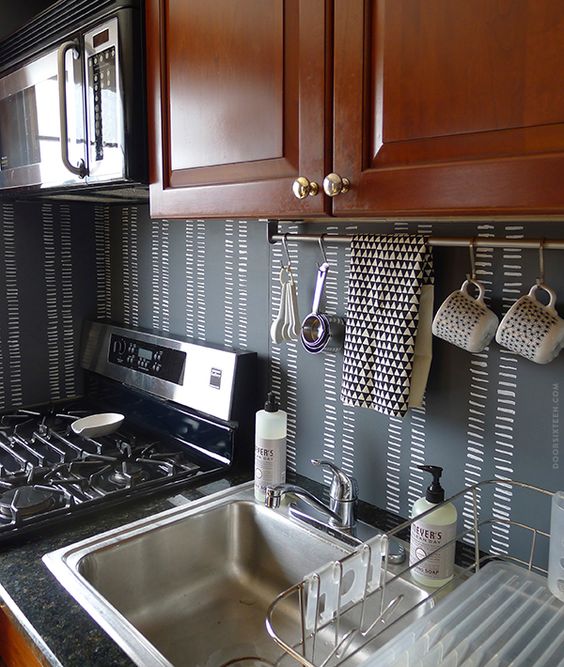 A chalkboard backsplash and rich colored wooden cabinets create a bold contrast
