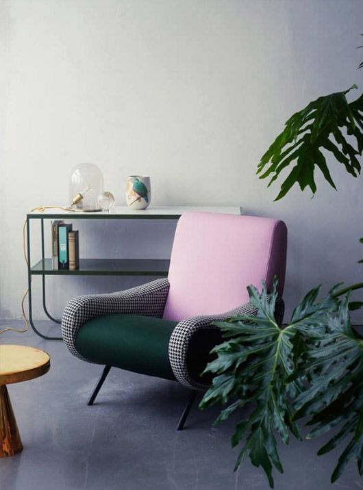 A cool mid century modern chair with a pink back, a dark green seat and gingham armrests