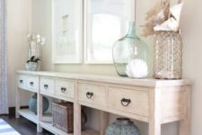 03 a long whitewashed console with sea-inspired artworks, large bottles and lanterns and shells