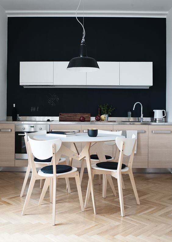 a contemporary kitchen with pale wood and white furniture and a chalkboard backsplash and blakc touches for a stylish look