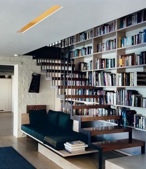 A cozy reading nook with built in shelves into the wall and an upholstered beach for reading