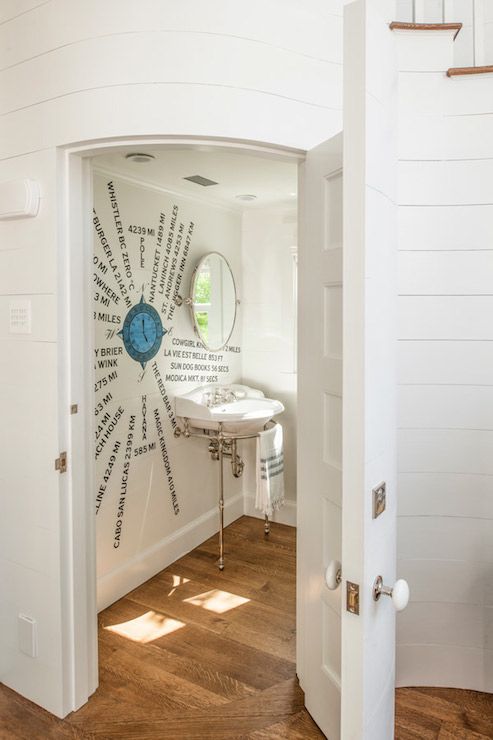 A creative sea inspired powder room with a window, an artwork on the wall and a round mirror