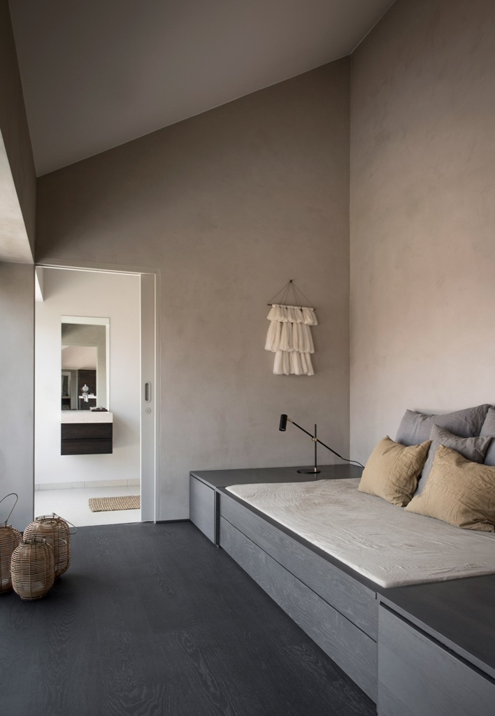 This room features light colored walls, a timber bed that can be transformed into a bench