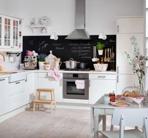 a cute white kitchen with a chalkboard backsplash and a mint dining set for a chic look