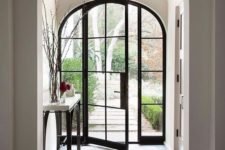 05 a fully glazed arched door with black metal framing is a chic and refined idea for any home