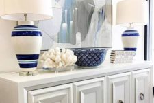 06 a chic white console, a large watercolor ocean-inspired artwork, striped lamps and a coral for a beach entryway