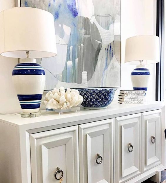A chic white console, a large watercolor ocean inspired artwork, striped lamps and a coral for a beach entryway