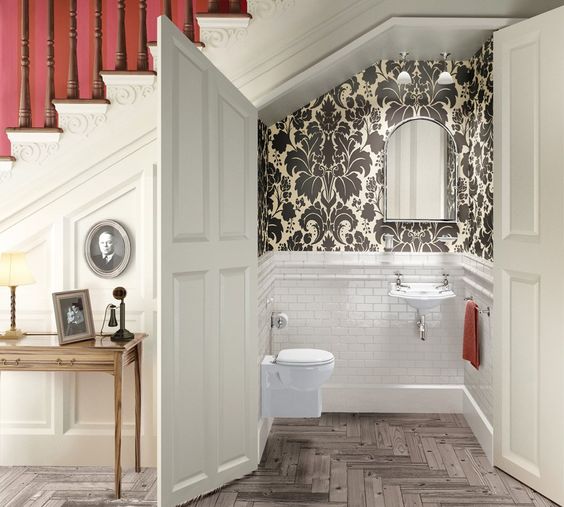 a powder room styled with white tiles and vintage printed wallpaper for a vintage feel