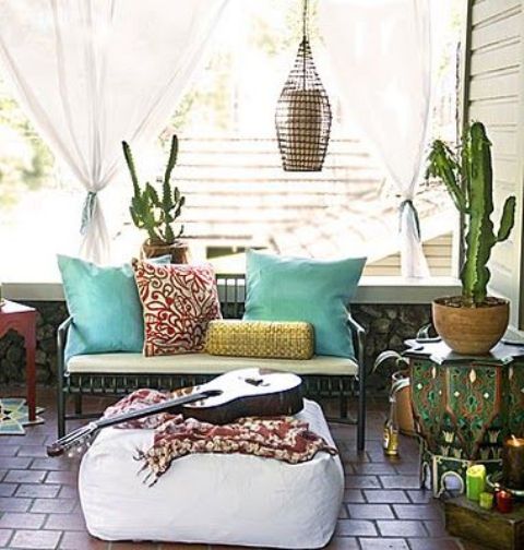 a boho porch with printed and colorful textiles, cacti and candle lanterns