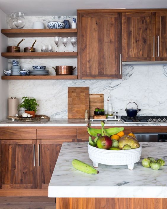 a rich-colored wooden kitchen contrasts the white marble backsplash and countertops and together they create a wow effect