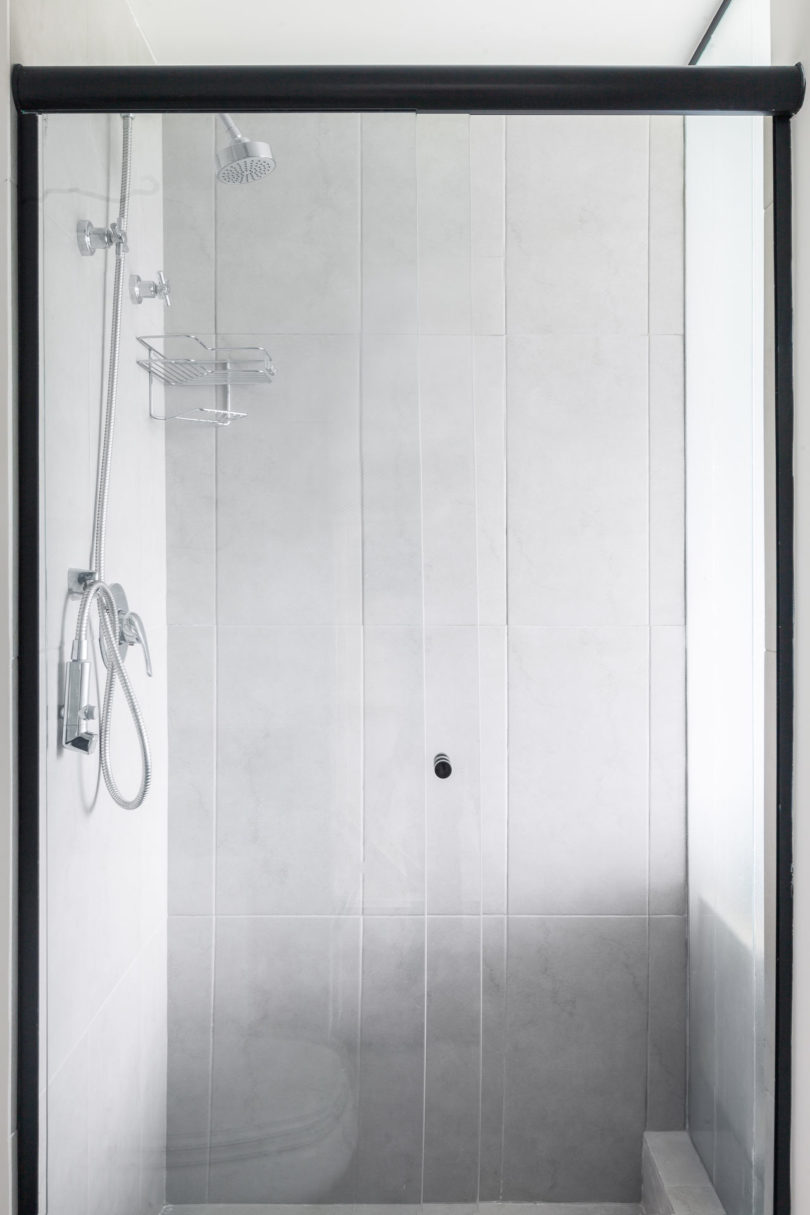 The small bathroom features a comfy shower clad with marble tiles