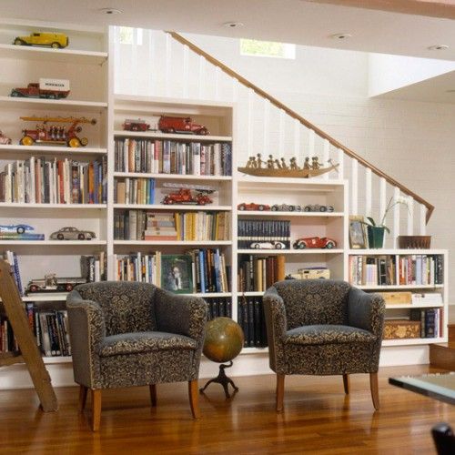 a built-in bookcase in the stairs and a couple of upholstered chairs for reading