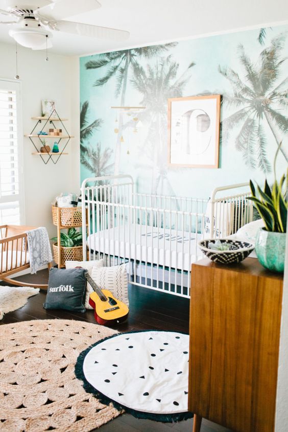 a tropical nursery for a boy, a blue palm print wall, printed rugs and warm-colored wooden furniture