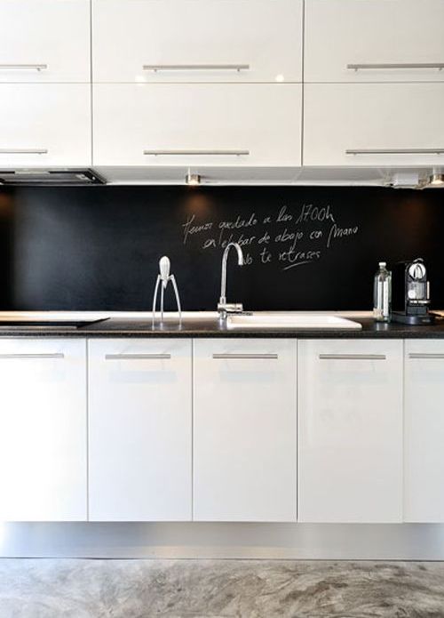 a modern white kitchen with a black chalkboard backsplash that helps it stand out and adds depth