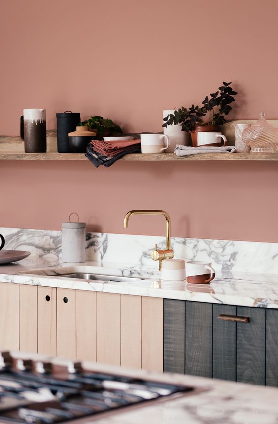 a terracotta pink kitchen with open shelving, wood plank cabinets and a white marble backsplash and countertop