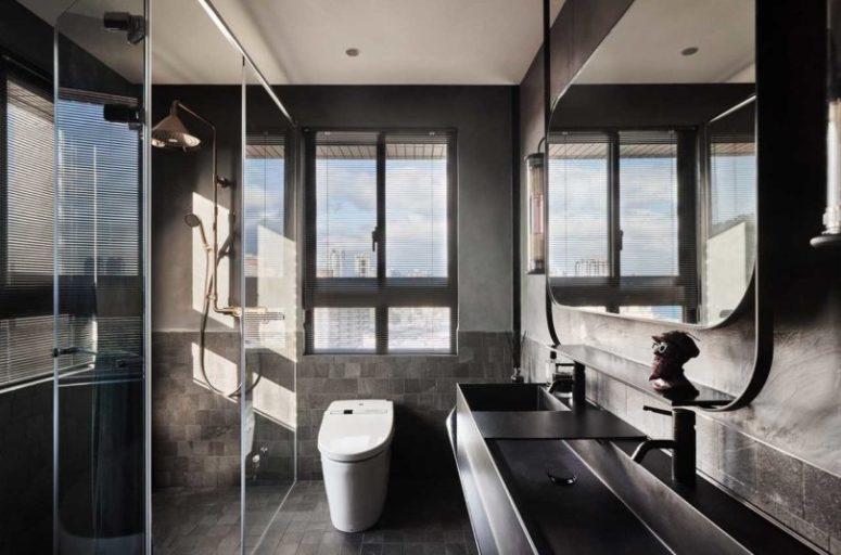 The bathroom is done in more industrial style, with grey tiles and metal sinks