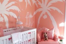 11 a colorful glam nursery with pink tropical print walls, a pink chair, a glam chandelier and a shiny ottoman