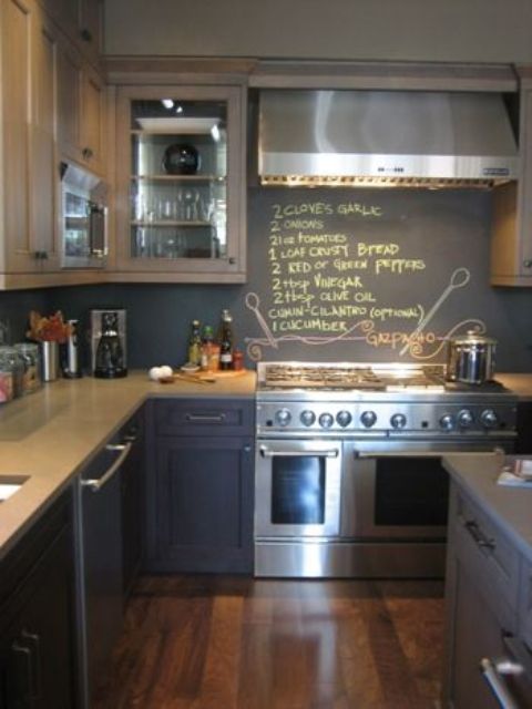 a navy kitchen with grey countertops and a chalkboard backsplash to chalk down the recipes