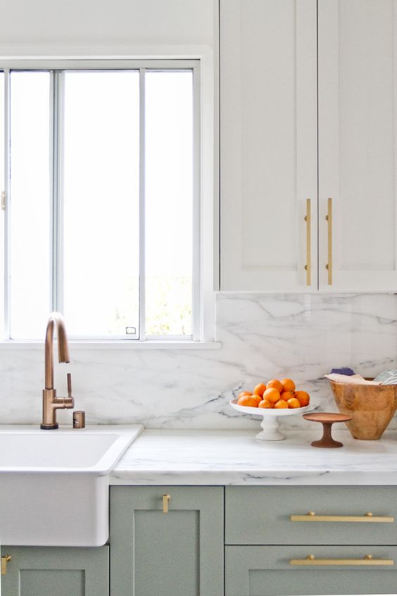 cream and light green cabinets with gilded handles and a white marble backsplash for a chic and refined accent