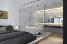 12 a contemporary bedroom with a bathtub separated with a glass divider and a sink stand behind it