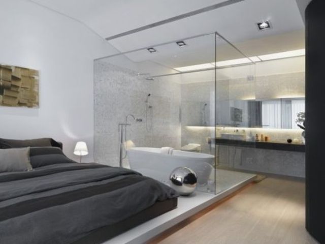 a contemporary bedroom with a bathtub separated with a glass divider and a sink stand behind it