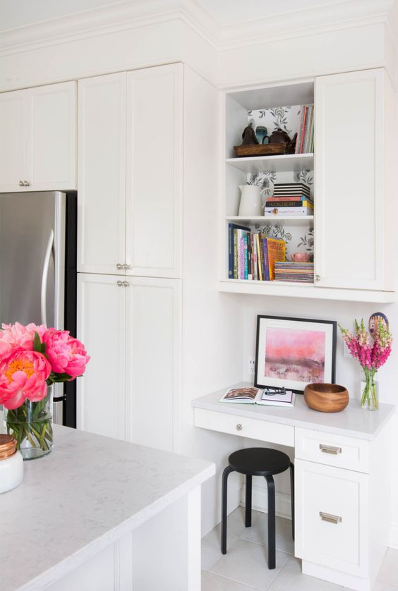 a contemporary kitchen in white with a small home office nook with drawers and a cabinet