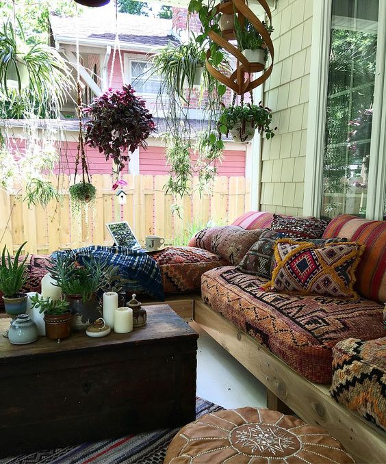 a boho gypsy porch with a wooden chest as a side table, a whole hanging garden and a corner sofa with printed upholstery