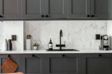 13 graphite grey cabinets contrast with a grey and white marble backsplash and countertops plus a black faucet